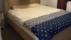A single bed with a wooden headboard, a white ceiling fan, and a dark curtain on the right. - Fantastic location townhouse close to beaches , shops , bus stop (Runaway Bay)
