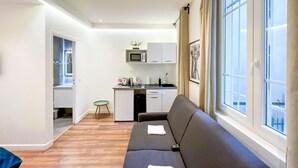 Un soggiorno moderno con un divano, un angolo cottura e un'ampia finestra.
