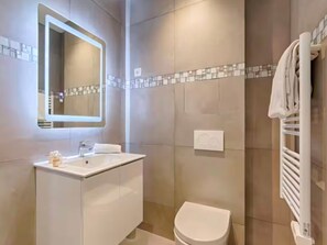 A modern bathroom with a large mirror, a white sink, and a toilet. - UrbanFlat 203 - 249 Saint Denis SD1 (París)