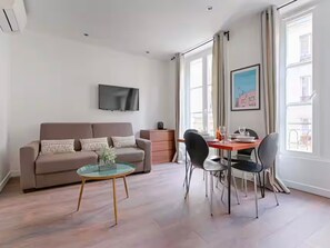 A modern living room with a sofa, a glass coffee table, and a dining area with chairs and a table. - UrbanFlat 203 - 249 Saint Denis SD1 (París)