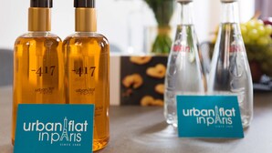 Zwei Flaschen Urban Flat Paris Parfüm und zwei Glasflaschen mit Etiketten stehen auf einem Tisch, vor ihnen liegt eine Karte.