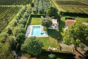Vista aérea de una propiedad con piscina, cancha de tenis y jardín.