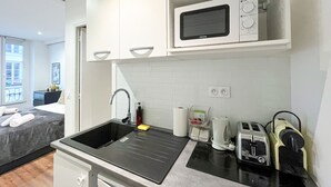 A compact kitchen with a sink, a microwave, a kettle, and a toaster. - UrbanFlat 206 - 249 Saint Denis SD1 (París)