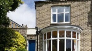 A two-story brick building with a bay window and a blue door. - Admiral’s Rest – Spacious - Historic Georgian Charm in the Heart of Broadstairs with Private Parking (Broadstairs)