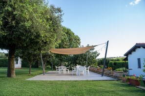 Un patio con mobili da esterno, una tenda parasole e piante in vaso.