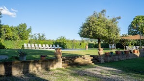 A garden with a seating area, a stone wall, and potted plants.