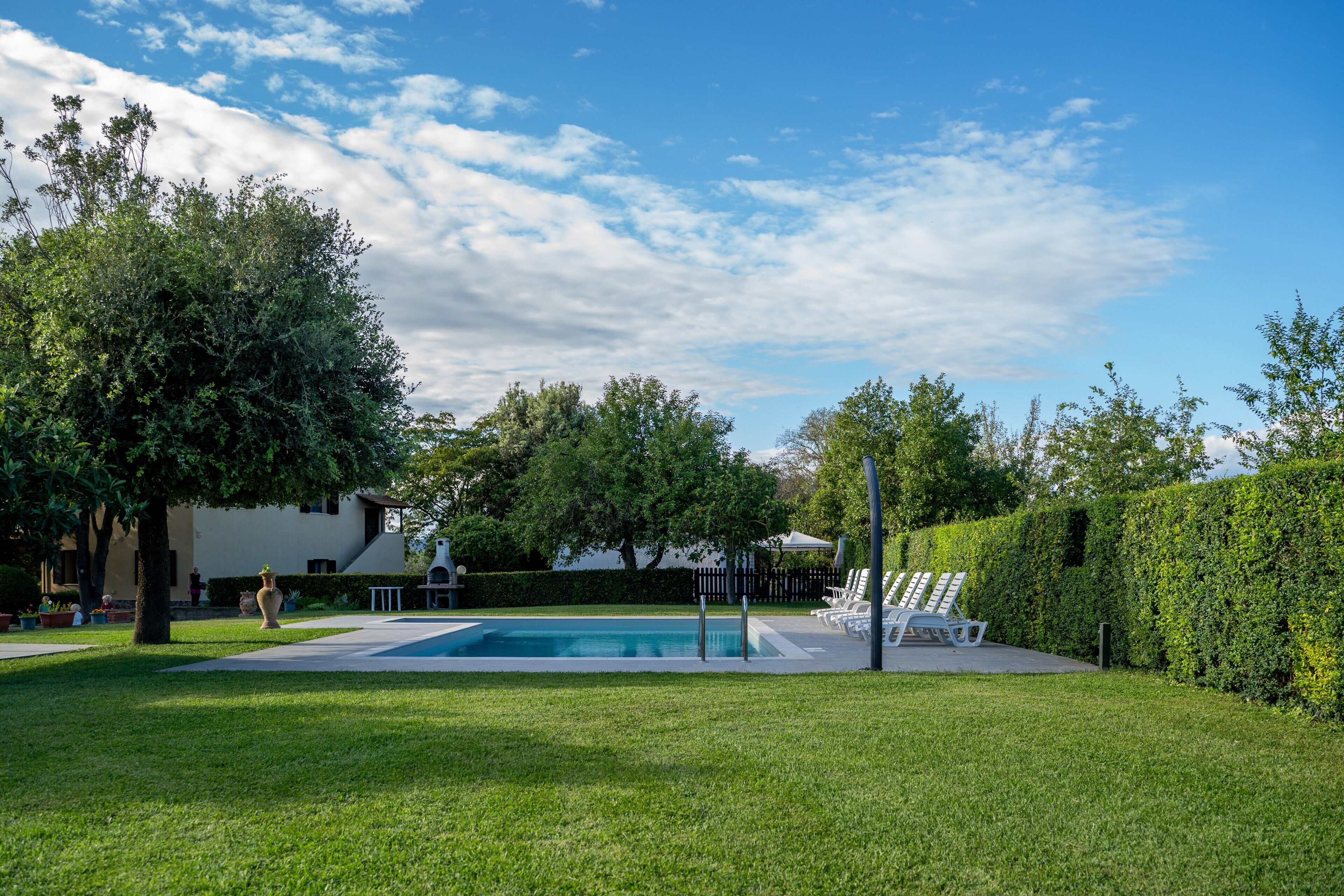 A swimming pool with lounge chairs, a lawn, and a building in the background.