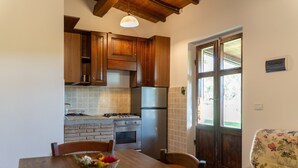 A kitchen with wooden cabinets, a refrigerator, a stove, and a dining table with chairs.
