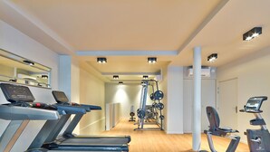 Een sportschool met loopbanden, een krachtapparaat en een hometrainer.
