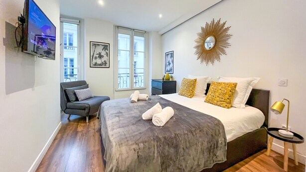 Un dormitorio moderno con una cama grande, un televisor montado en la pared y vistas al balcón.