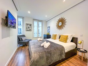 A modern bedroom with a large bed, a TV mounted on the wall, and a balcony view. - UrbanFlat 209 - 249 Saint Denis SD1 (París)