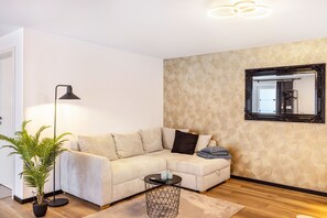 Uma sala de estar moderna com sofá, luminária de chão, planta em vaso e mesa de centro redonda.