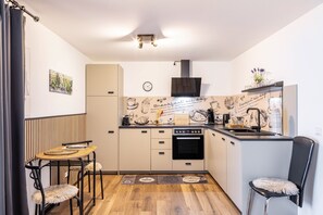 A compact kitchen with a dining area, a built-in oven, and a clock on the wall.