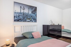 Un dormitorio con cama, mesitas de noche, un espejo y un cuadro colgado en la pared.