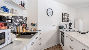 Eine moderne Küche mit weißen Schränken, einer schwarzen Uhr und einer Kaffeemaschine.