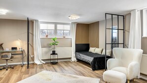 Ein modernes Schlafzimmer mit Bett, Schreibtisch, Stuhl, Heizkörper und Fenster.