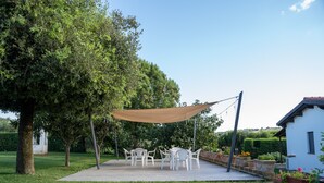 A patio with outdoor furniture, a shade sail, and potted plants. - Apartment 'Melograno' with Shared Pool, Wi-Fi and Air Conditioning (Campagnatico)