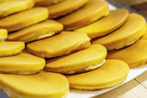 A plate of golden-brown pancakes stacked on a white plate. - Sant'Angelo Station (Naples)