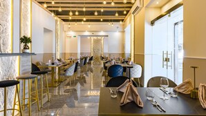 A modern restaurant with a long counter, multiple tables, and bar stools. - Sant'Angelo Station (Naples)