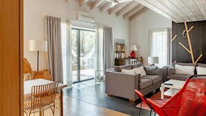 Amplia sala de estar con un sofá moderno, una zona de comedor con mesa y sillas, y un ventanal que proporciona luz natural.