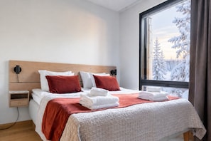 A modern bedroom with a large window, a wooden headboard, and neatly arranged towels. - Central Lux Apartment D19 by Aavalevi (Levi)