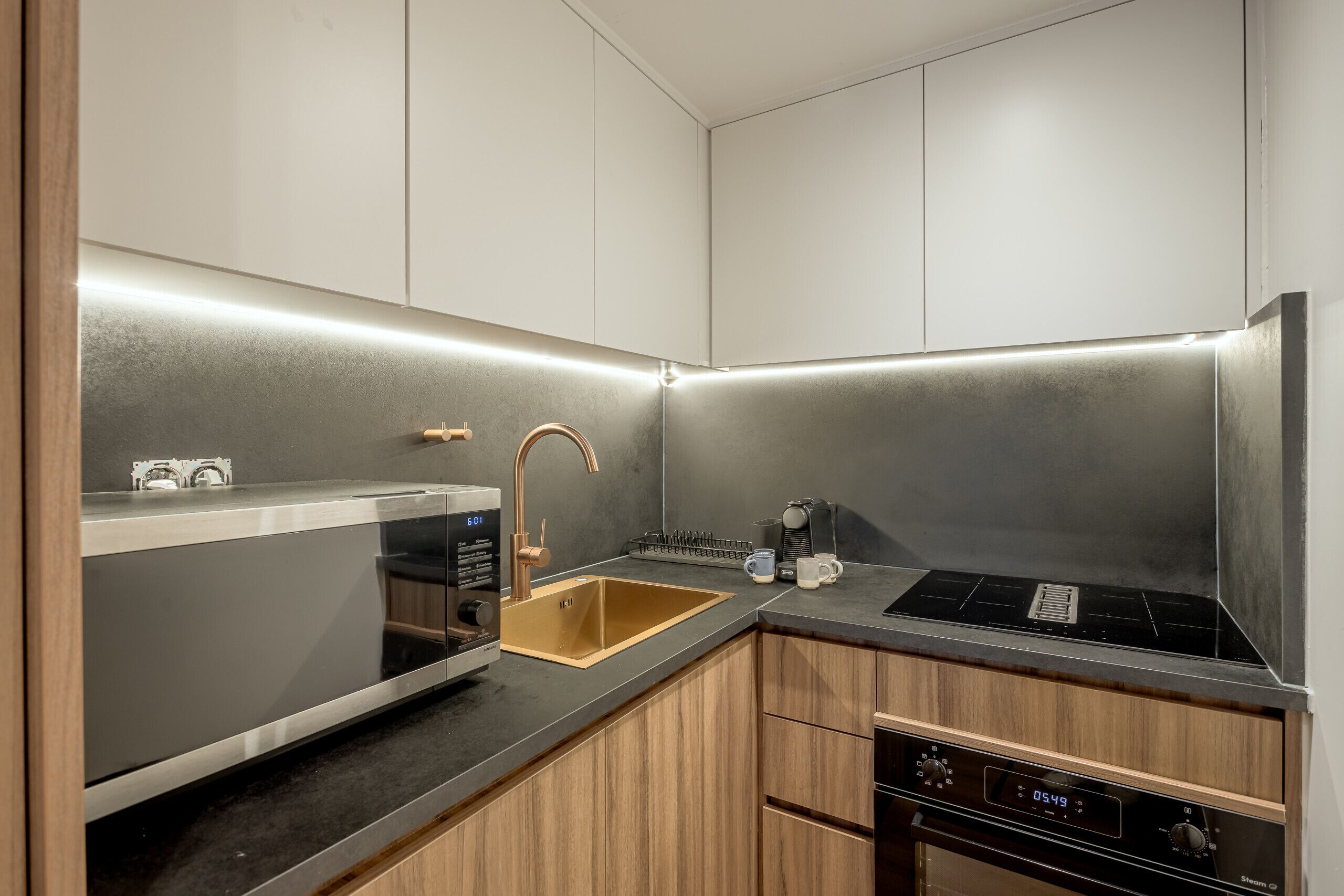 Una cocina moderna con un lavamanos de acero inoxidable, un horno empotrado y una cafetera.