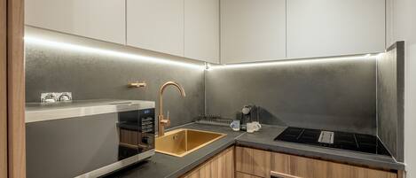 Una cocina moderna con un lavamanos de acero inoxidable, un horno empotrado y una cafetera.