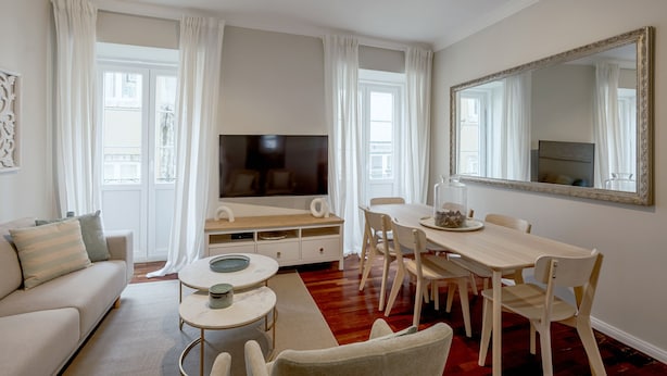 Una sala moderna con un sofá, una televisión, una mesa de comedor y sillas.