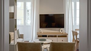 Una sala de estar moderna con un televisor de pantalla plana, una mesa de centro redonda y un sofá.