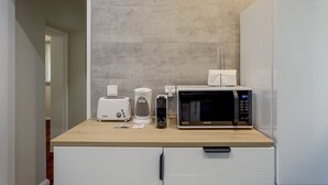 Una cocina con microondas, tostadora y cafetera sobre una encimera de madera.