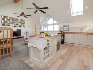 A modern kitchen with a central island, a dining area with a TV, and a ceiling fan. - 33 Fordh Tobmen (St. Agnes)