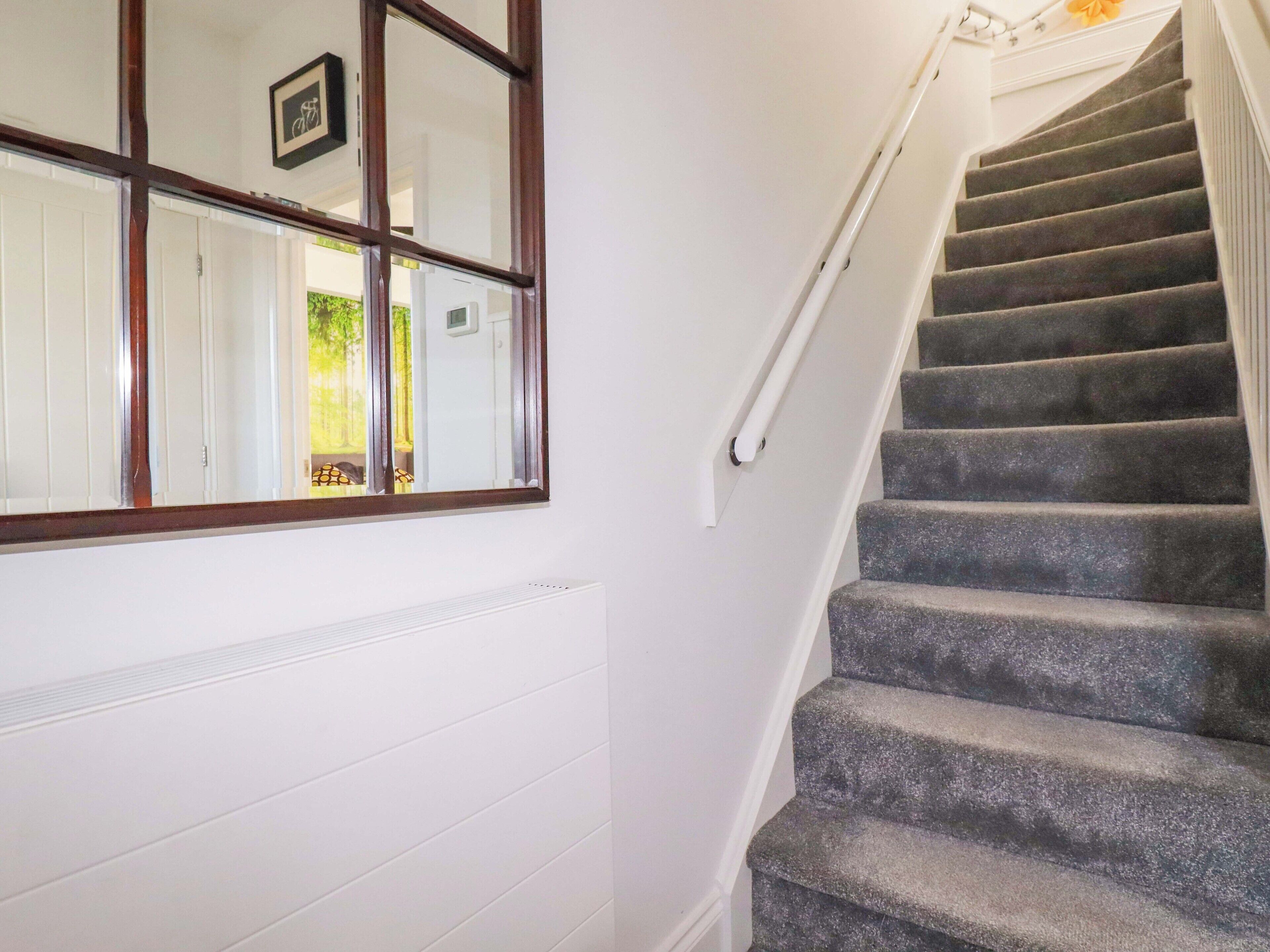 Un escalier avec une rampe, une fenêtre ornée d’un cadre et un radiateur en dessous.