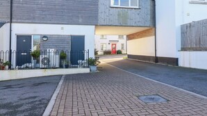 Une rue résidentielle bordée de maisons à deux étages, dont l’une est dotée d’un garage, d’une porte rouge et d’une allée.