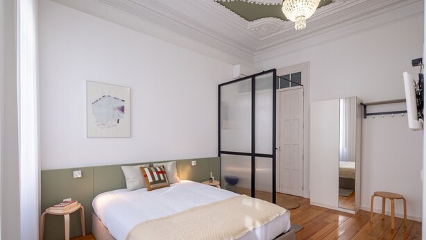 A bedroom with a bed, bedside table, chair, and a mirror. - Braga Essence Studio by Minhos Guest (Braga)