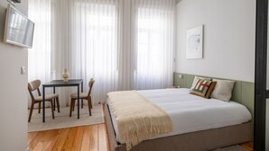A bedroom with a bed, a desk with chairs, and a TV on the wall. - Braga Essence Studio by Minhos Guest (Braga)