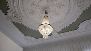 A ceiling with ornate plasterwork and a crystal chandelier. - Braga Essence Studio by Minhos Guest (Braga)