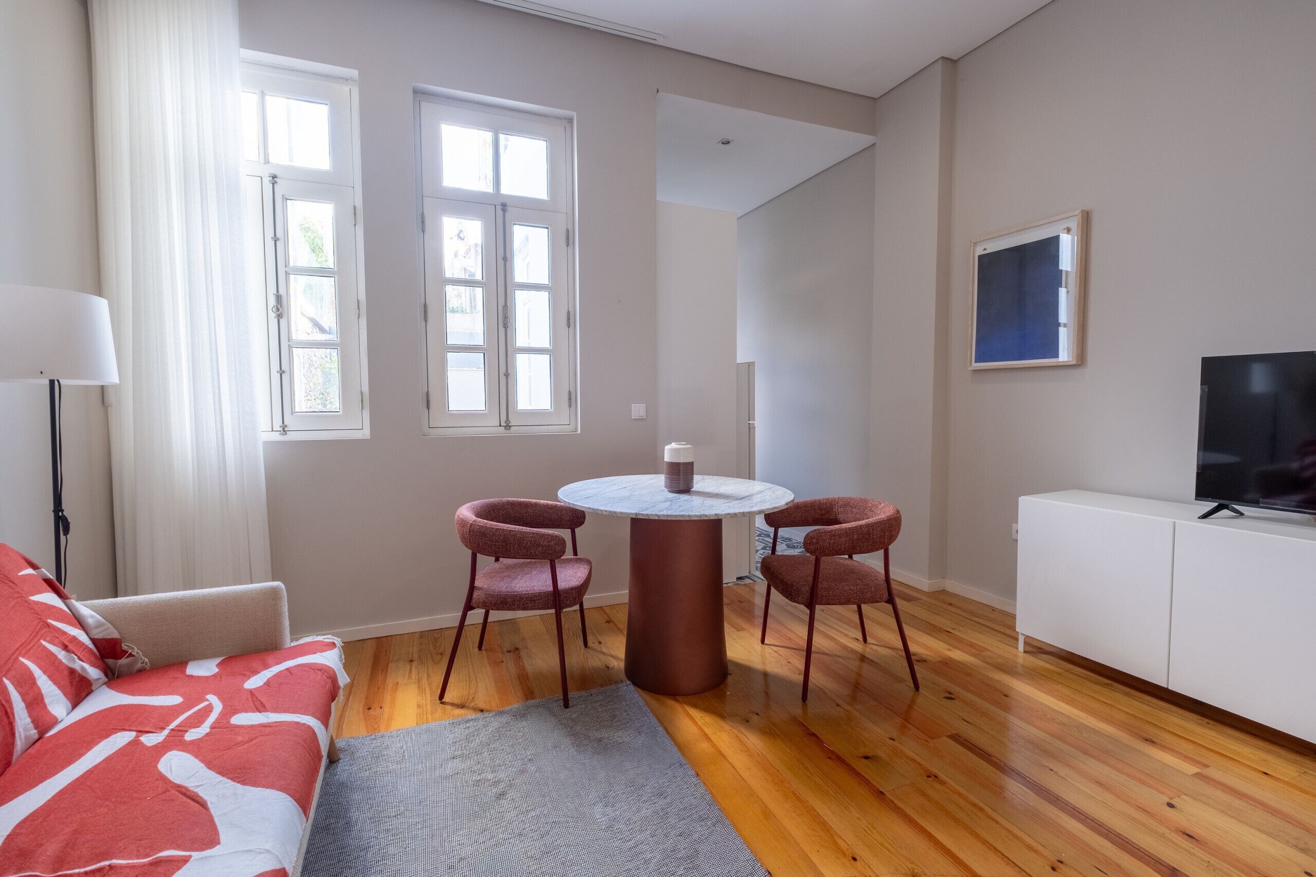 En moderne stue med sofa, sofabord, to stole, fjernsyn og spisebord.