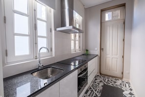 A modern kitchen with a stainless steel sink, a built-in oven, and a window above the sink. - Braga Essence Apartment By Minhos Guest (Braga)