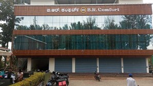 A building with a sign reading "B.R. Comfort" and a logo. There are parked motorcycles and a person standing in front. - BR Comfort (Bengaluru)
