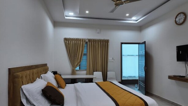 A modern hotel room with a large bed, a desk, and a television. - BR Comfort (Bengaluru)