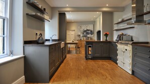 Una cucina moderna con mobili grigi, pavimento in legno e scaffali a muro.