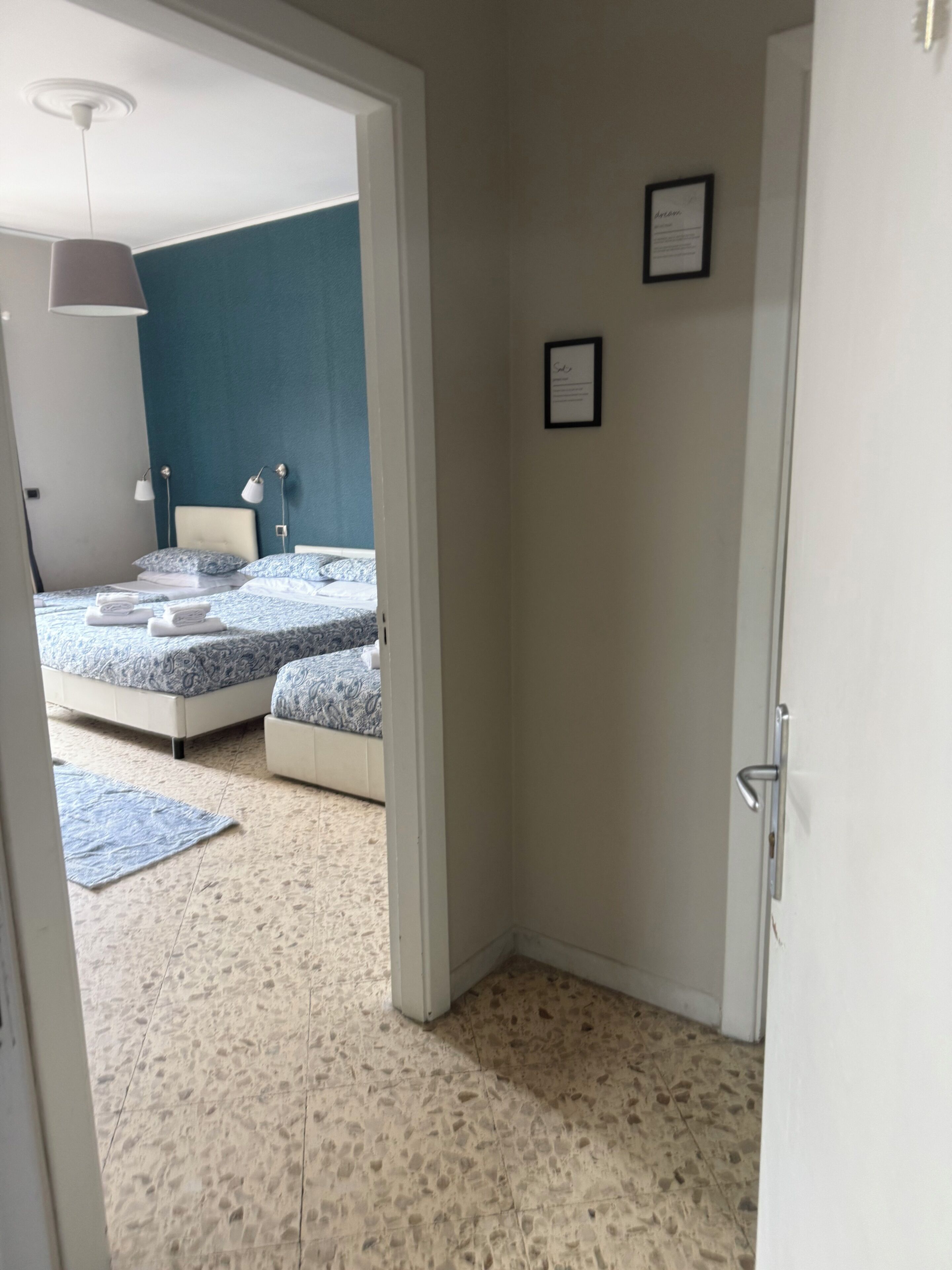 Une pièce avec un lit, des lampes de chevet, un tableau encadré au mur et une porte.