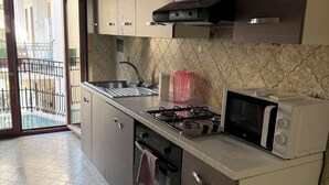 Une cuisine équipée d’une cuisinière à gaz, d’un four, d’un four à micro-ondes et d’une fenêtre donnant sur un balcon.