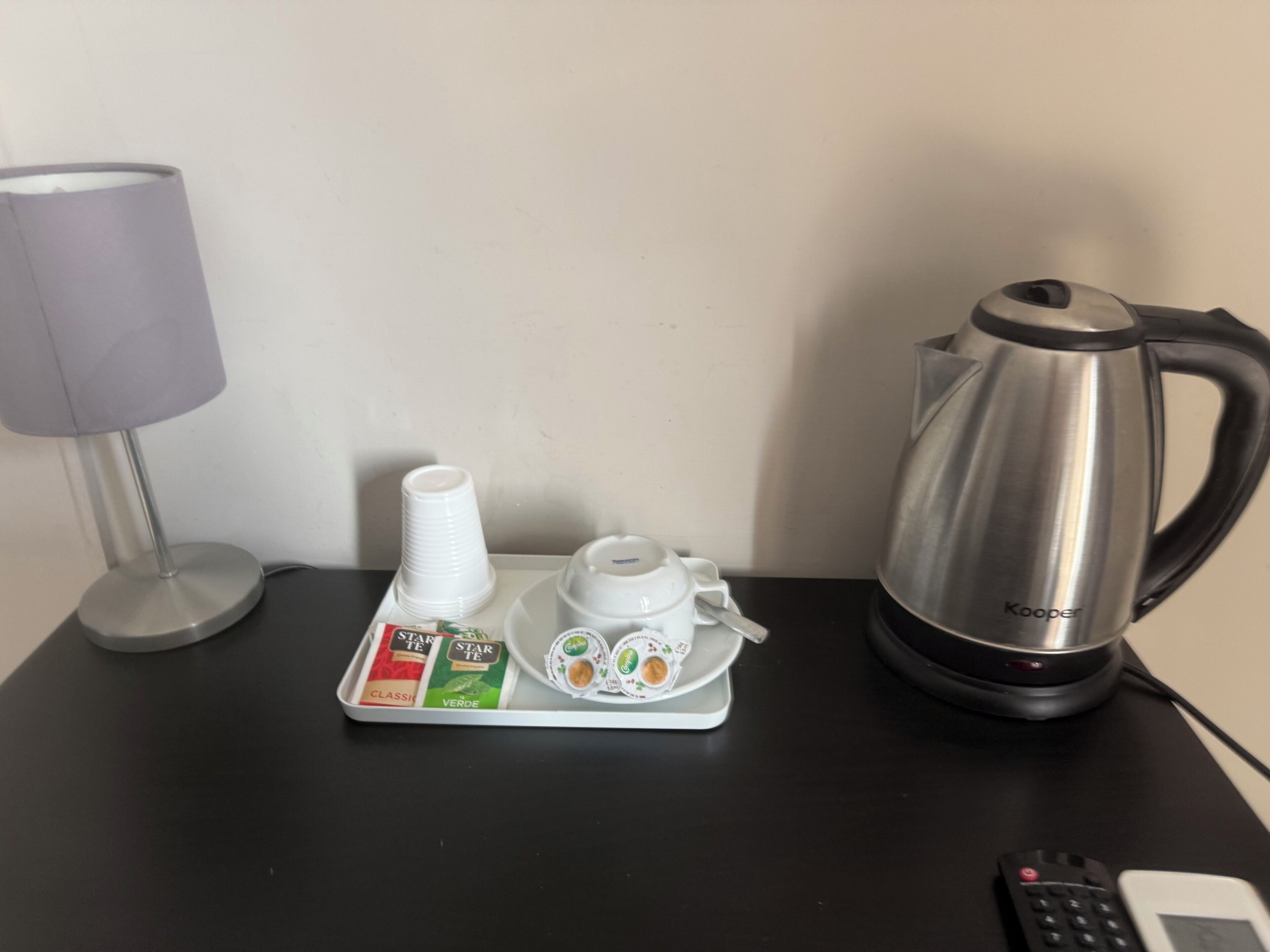 A tray with coffee cups, a teapot, and coffee pods on a table.
