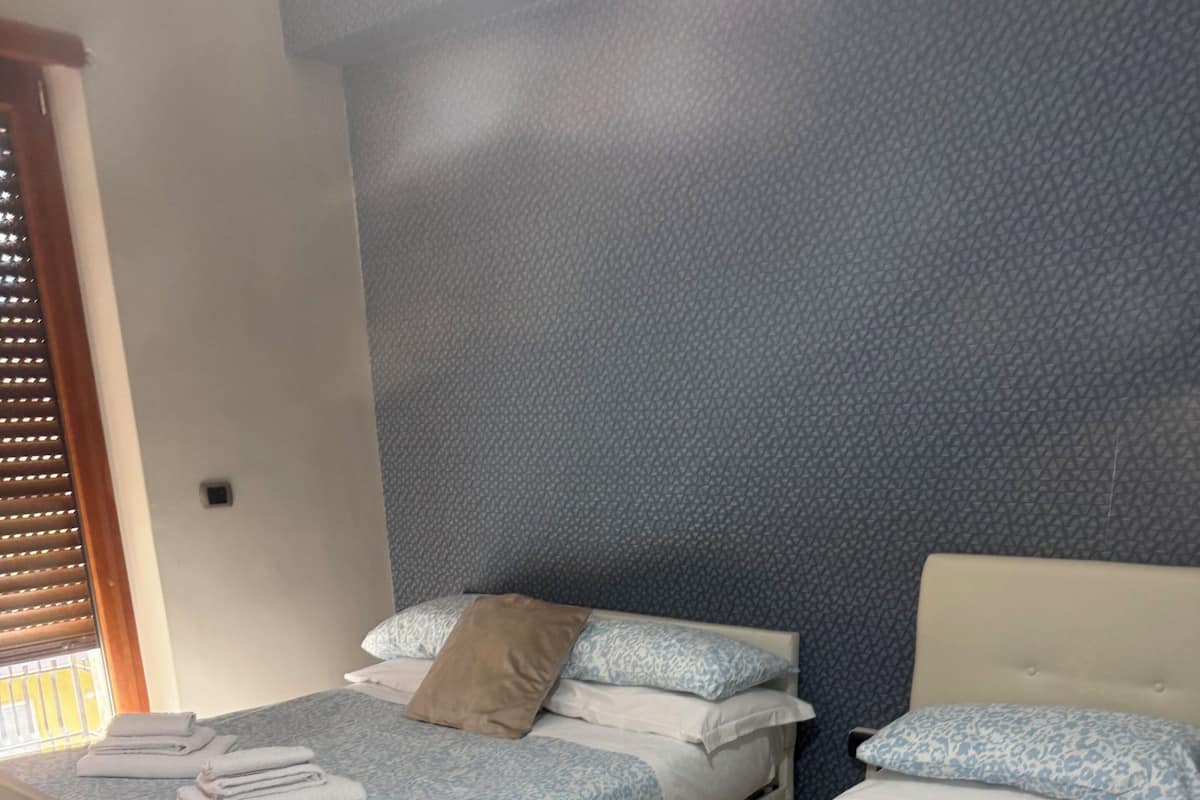 Habitación de hotel con dos camas, cada una con colcha estampada, almohadas y toallas.