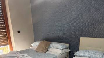 Habitación de hotel con dos camas, cada una con colcha estampada, almohadas y toallas.
