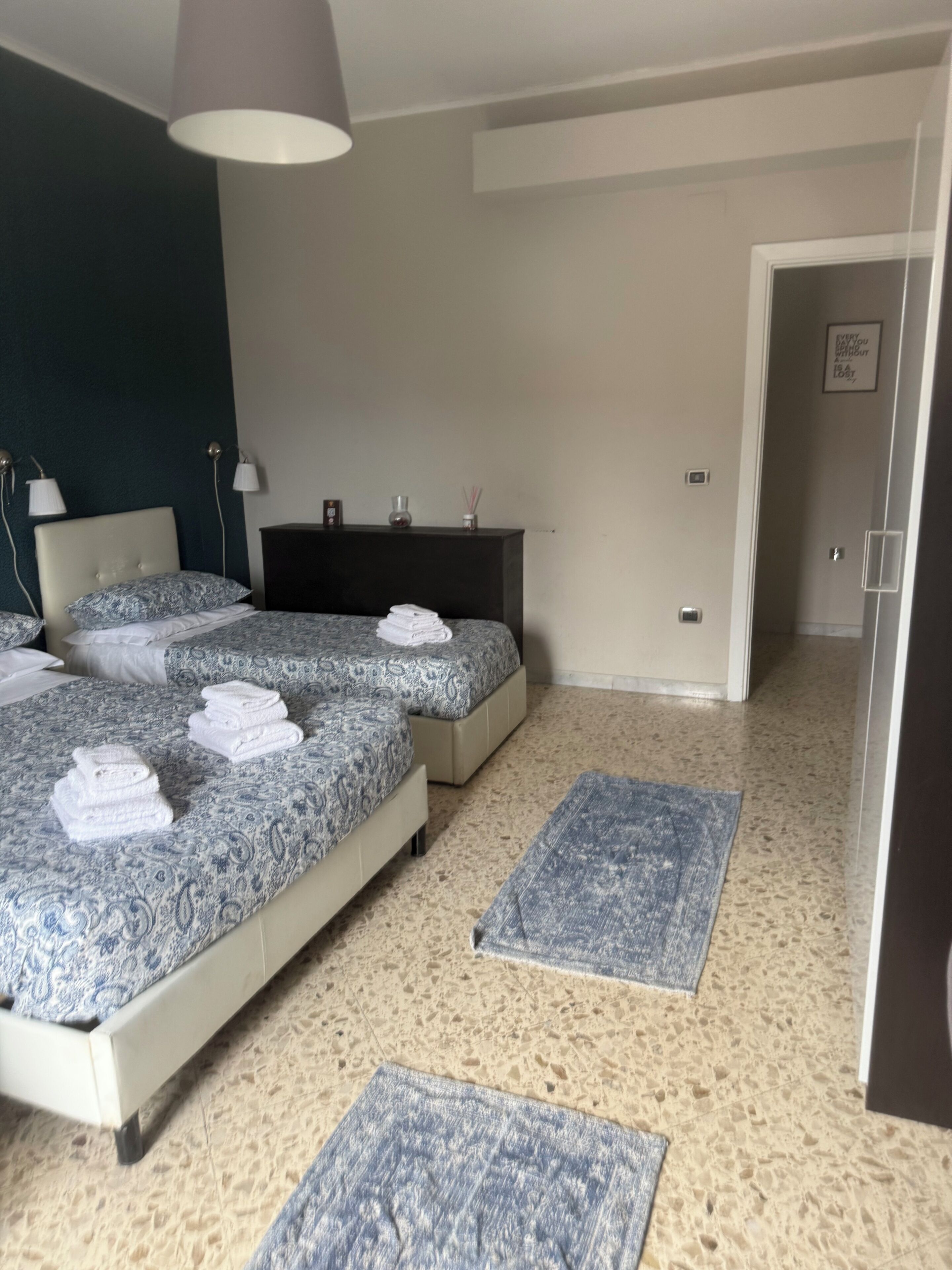 A bedroom with a bed, bedside tables, a dresser, and a door leading to another room.