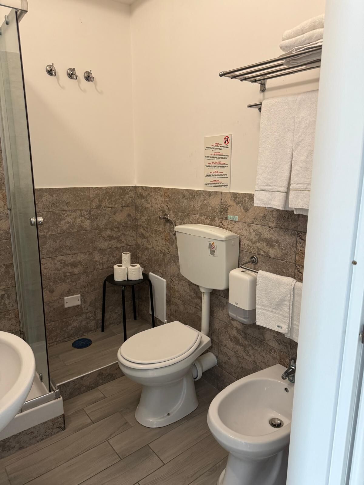 Un baño con inodoro, bidé y cabina de ducha de vidrio.