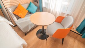 A modern hotel room with a sofa, two chairs, a small round table, and a bed. - Home Inn Huayi Select Collection Hotel  (Tongzhou)