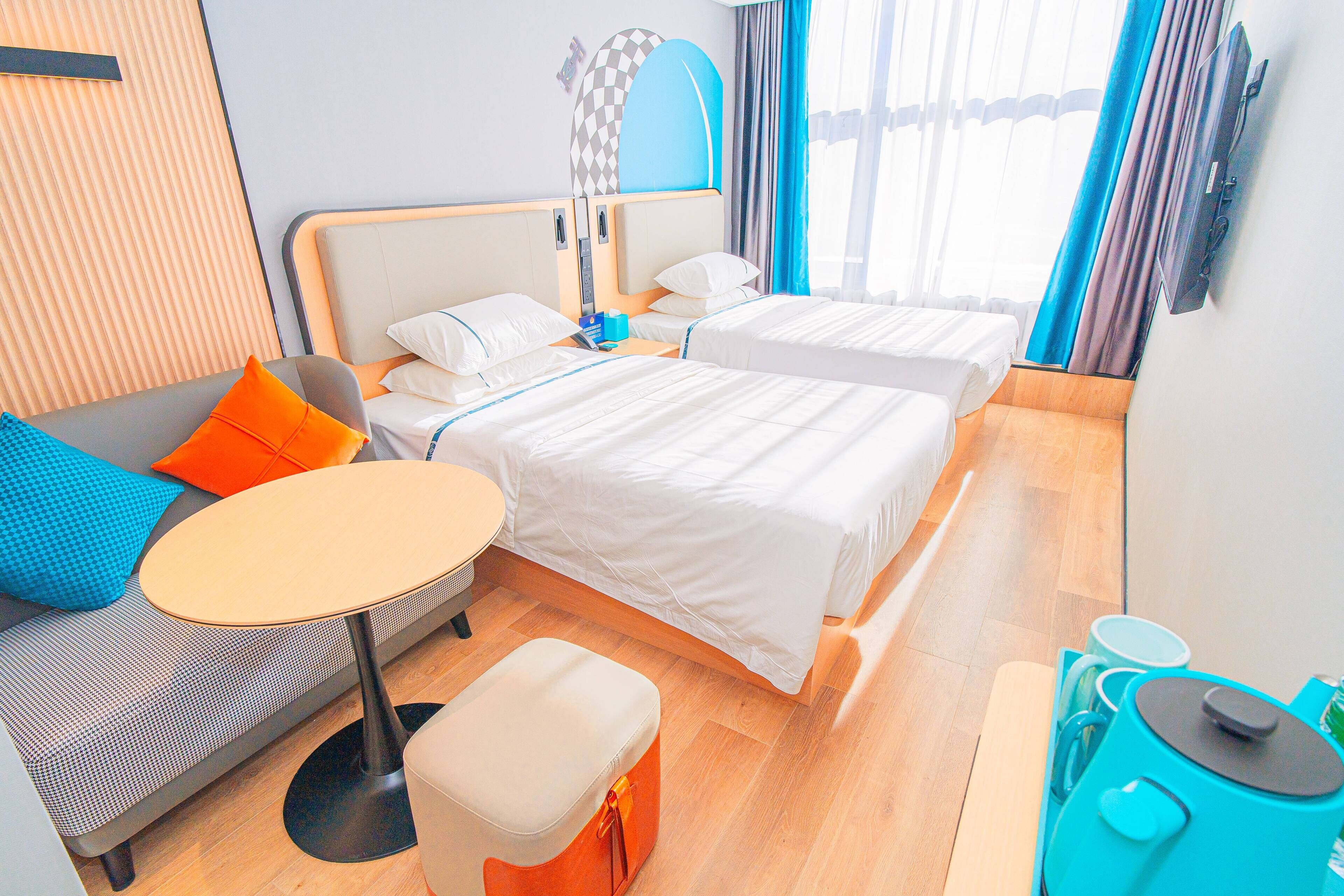 A hotel room with two beds, a sofa, a small table, and a TV.